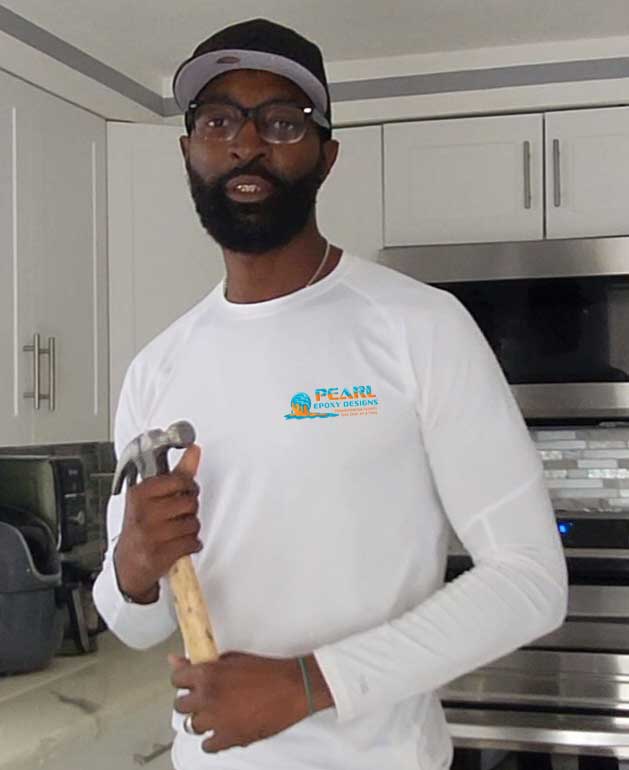 Alphonso Evans standing in a kitchen holding a hammer.