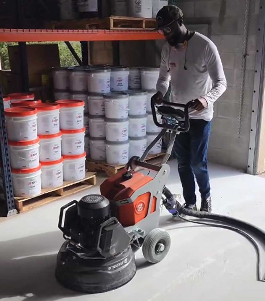 Alphonso using a concrete sander on a garage floor.