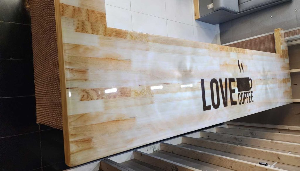 Epoxy covered bar with the word LOVE COFFEE with a coffee cup in the center of it.