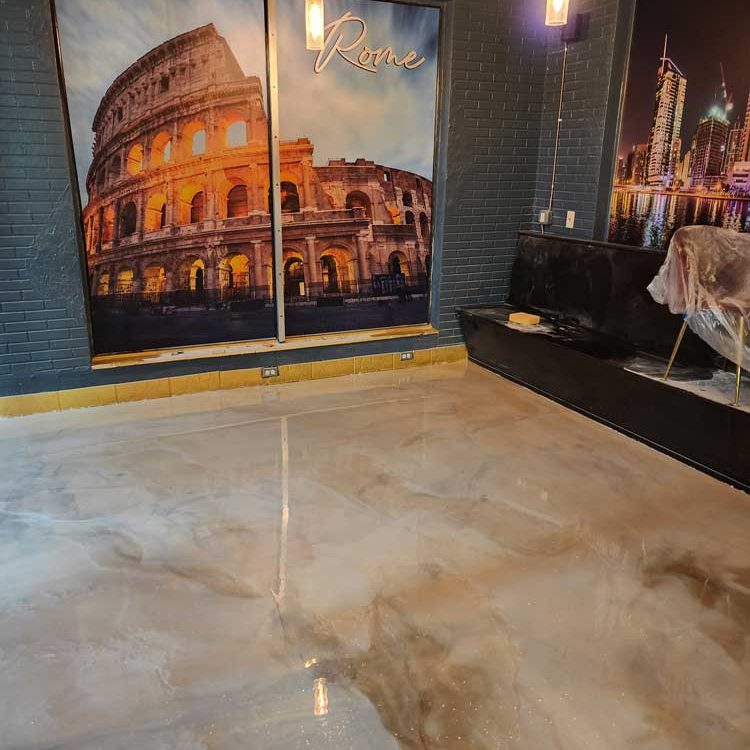 Gold and cream colored paint swirled in epoxy pain on a floor with a large poster of ROME on the wall.