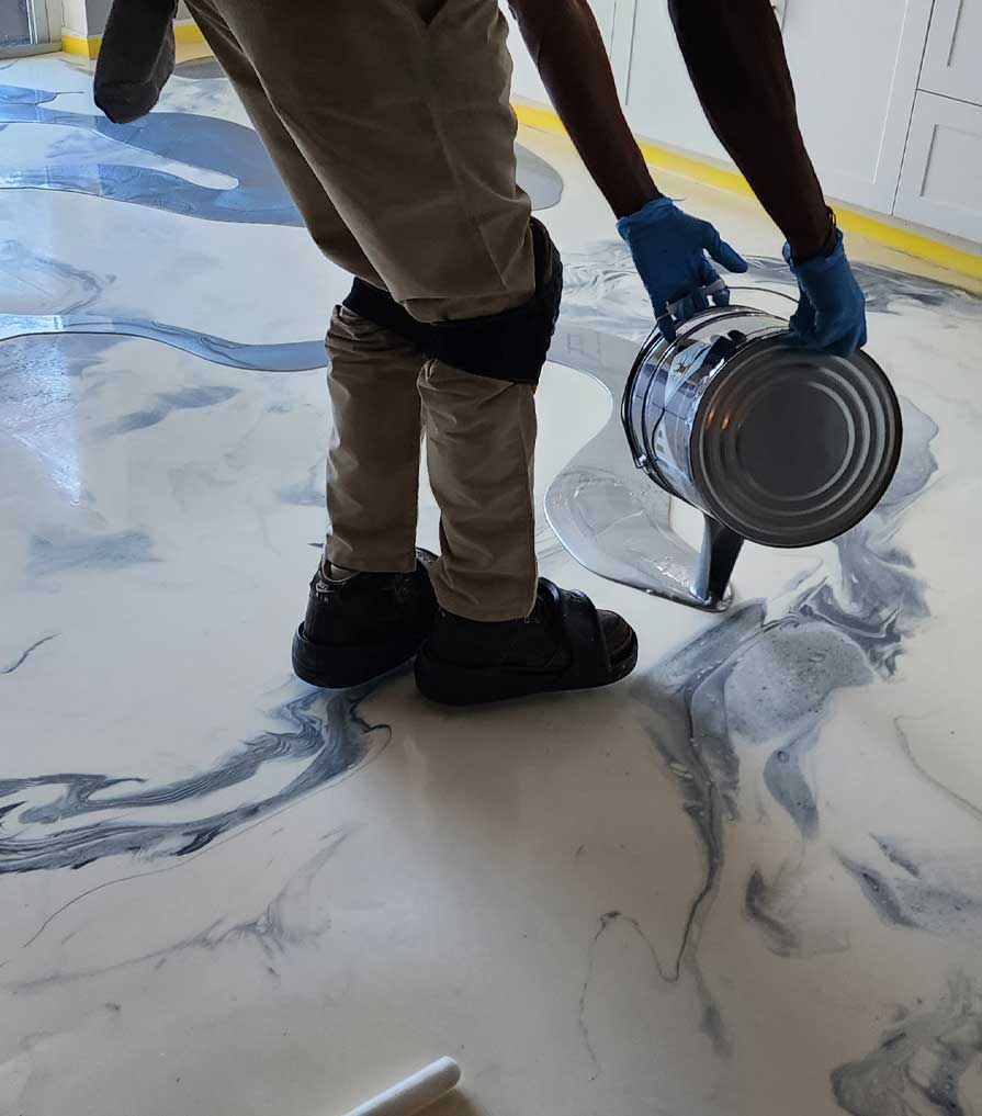 Alphonso pouring epoxy paint onto a floor.