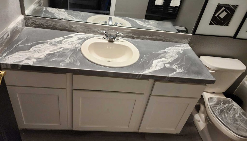 Gray and white epoxy paint swirled on a bathroom countertop and toilet seat.