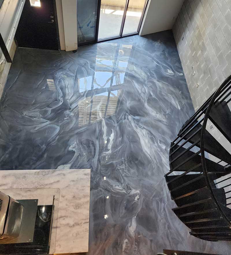 Gray and white epoxy paint swirled on floor with a spiral staircase.